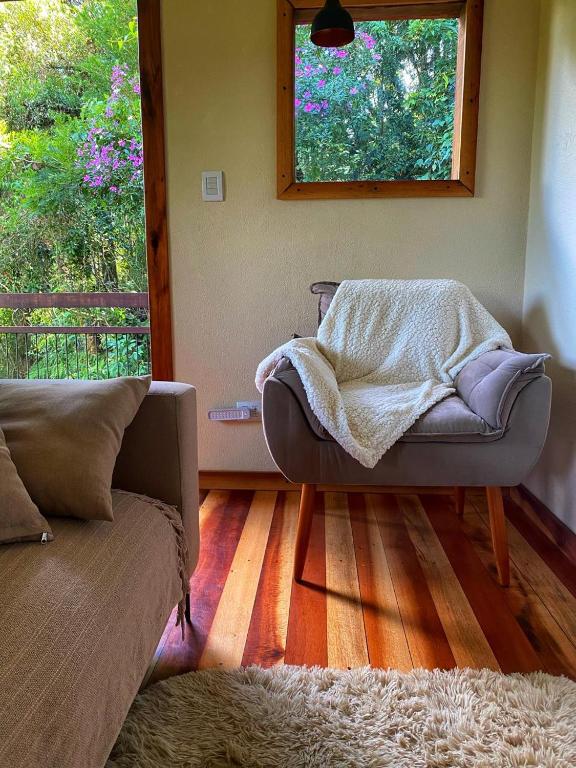 a living room with a couch and a window at Villa Mantiqueira - Studio II - Com lareira e área verde in Campos do Jordão