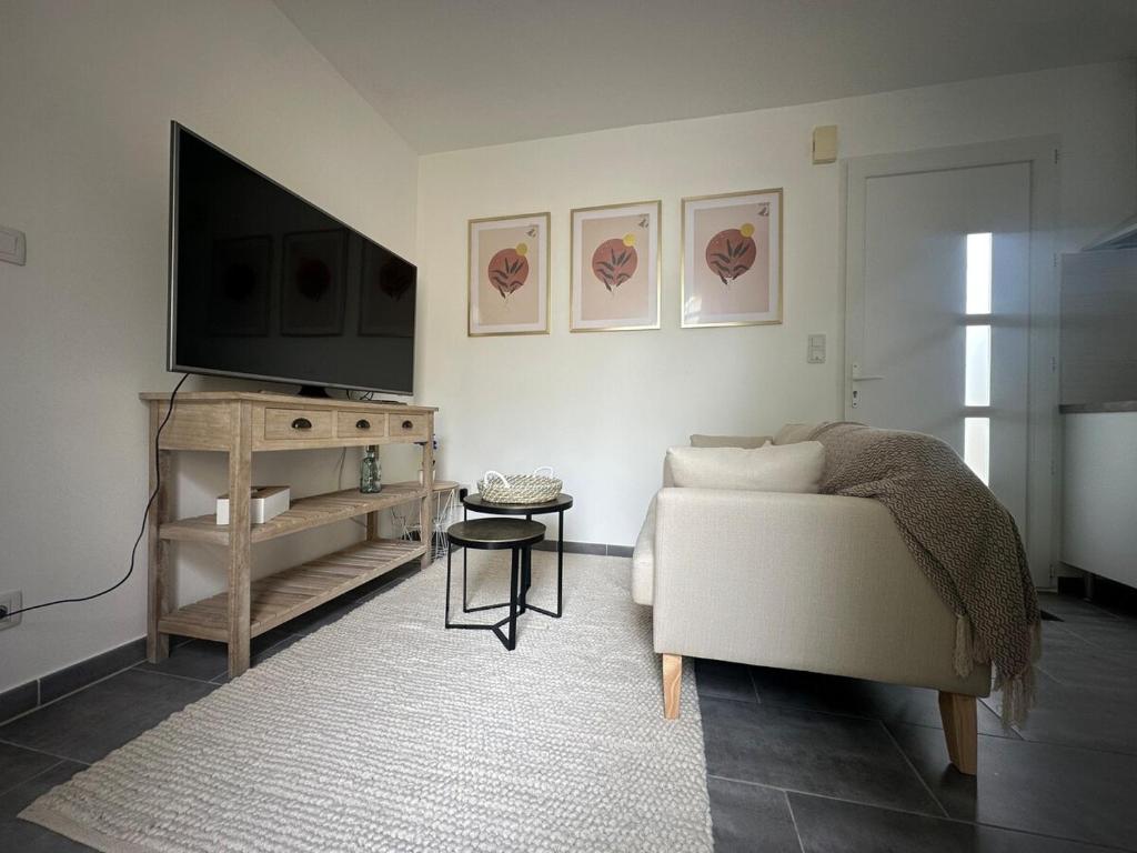 a living room with a couch and a flat screen tv at A l'ombre du Marronnier in Préfailles
