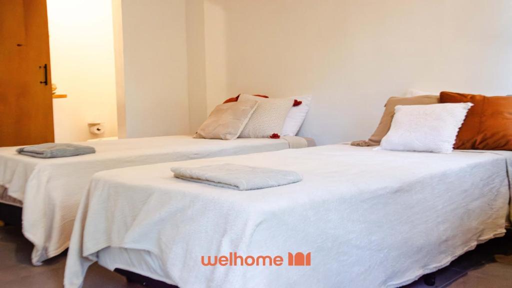 two beds in a room with white sheets and pillows at Suíte em São Francisco Xavier ao Redor da Natureza in São Francisco Xavier