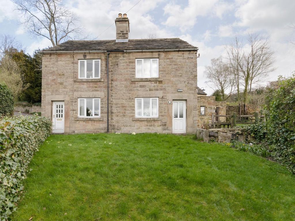 a brick house with a grassy yard in front of it at Bank Top Cottage in Hathersage