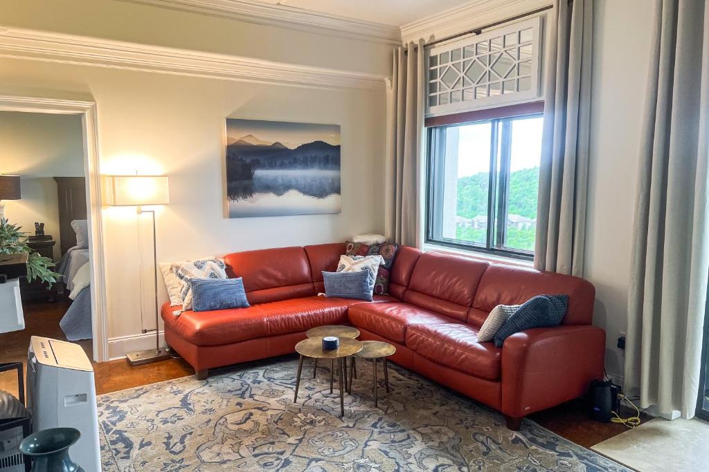 a red leather couch in a living room with a window at Misty Morning in Sugar Mountain