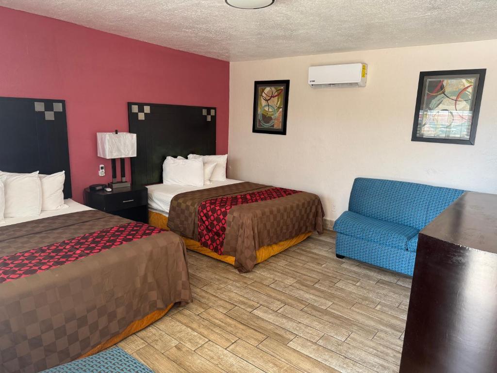 a hotel room with two beds and a blue chair at Western Motel in El Centro
