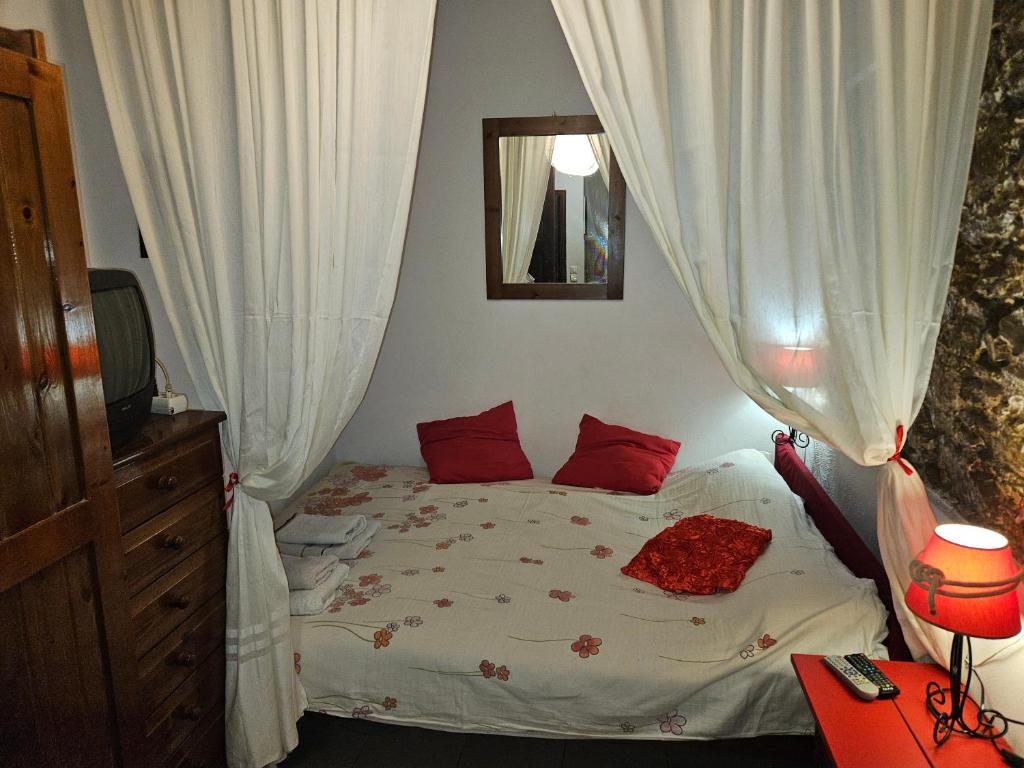 a bedroom with a bed with white curtains and a mirror at small sweet home romantic in Ermoupoli