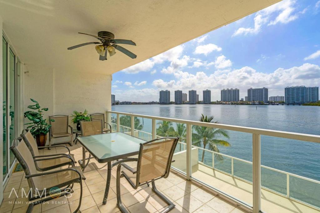 a balcony with a table and chairs and a view of the water at Bay View Oasis with Balcony & Free Parking Sunny Isles Beach in Sunny Isles Beach
