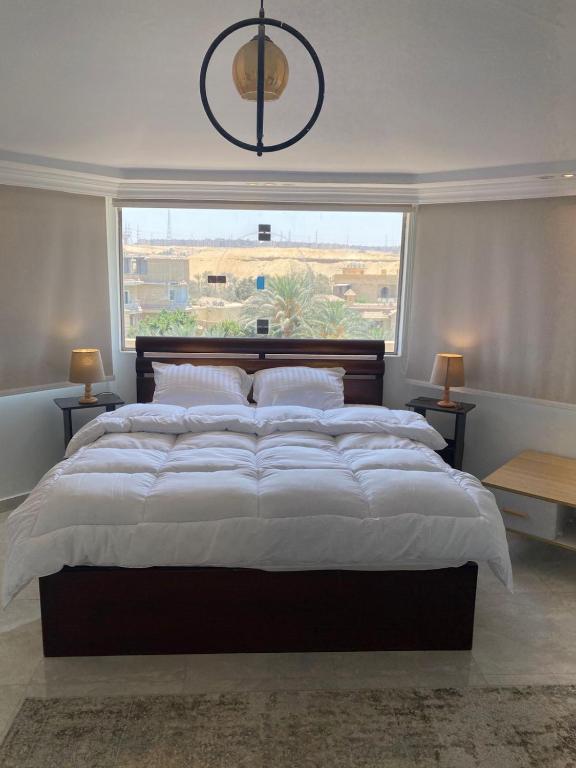a large bed in a bedroom with a large window at Pyramids Top Roof in Ghaţāţī
