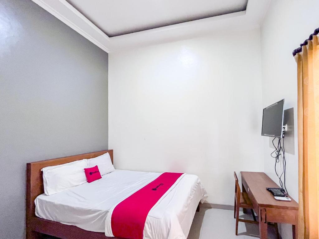 a small bedroom with a bed and a desk at RedDoorz Syariah near Suncity Waterpark Sidoarjo in Sidoarjo