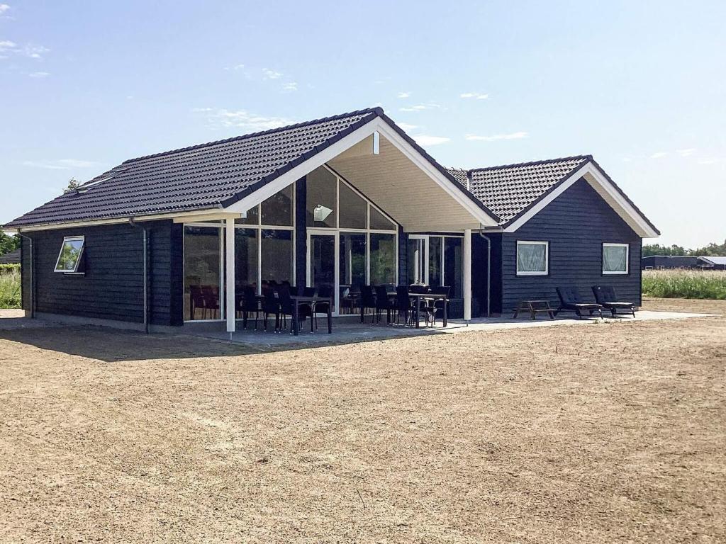une maison noire avec des tables et des chaises devant elle dans l'établissement 5 star holiday home in Idestrup, à Bøtø By