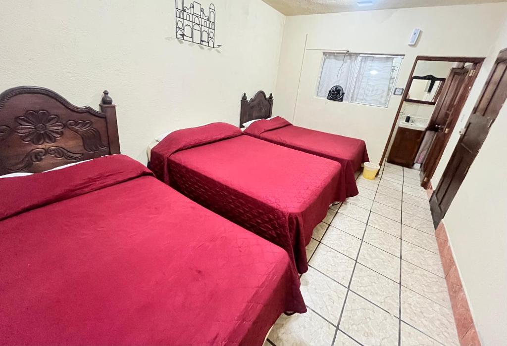 two beds in a room with red sheets at Jireh guesthouse in Antigua Guatemala