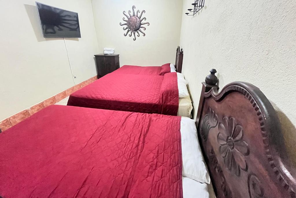 a bedroom with two beds with red comforter at Jireh guesthouse in Antigua Guatemala
