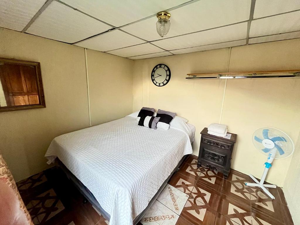 a bedroom with a bed and a clock on the wall at Jireh guesthouse in Antigua Guatemala