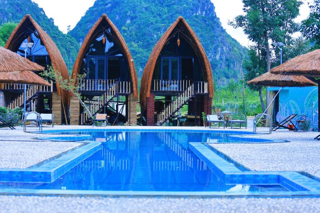 a resort with a swimming pool and mountains in the background at Cat Ba Holiday Retreat in Cat Ba