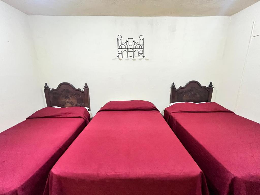 two beds in a room with red sheets at Jireh guesthouse in Antigua Guatemala