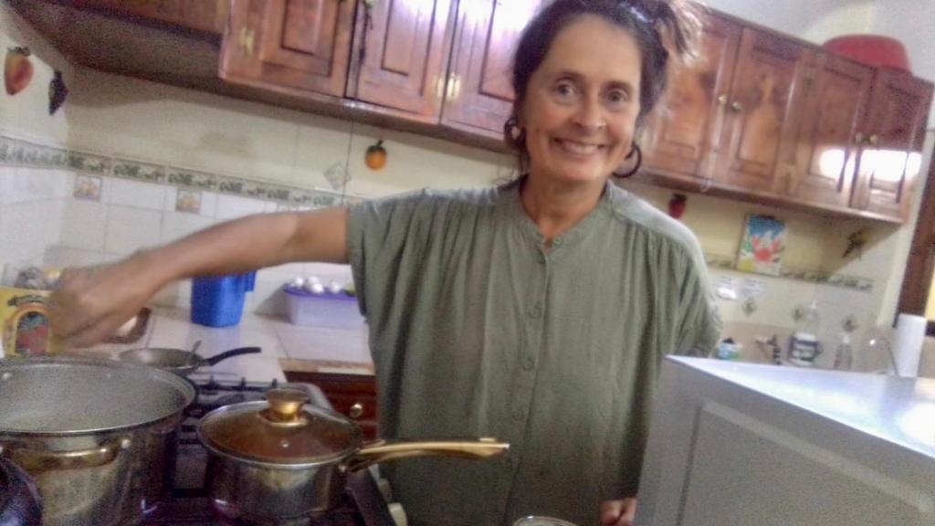 a woman standing in a kitchen stirring a pot at Jireh guesthouse in Antigua Guatemala