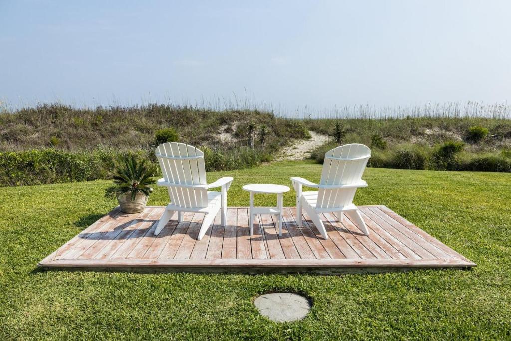 twee witte stoelen en een tafel op een houten terras bij Taylor Cottage home in Atlantic Beach