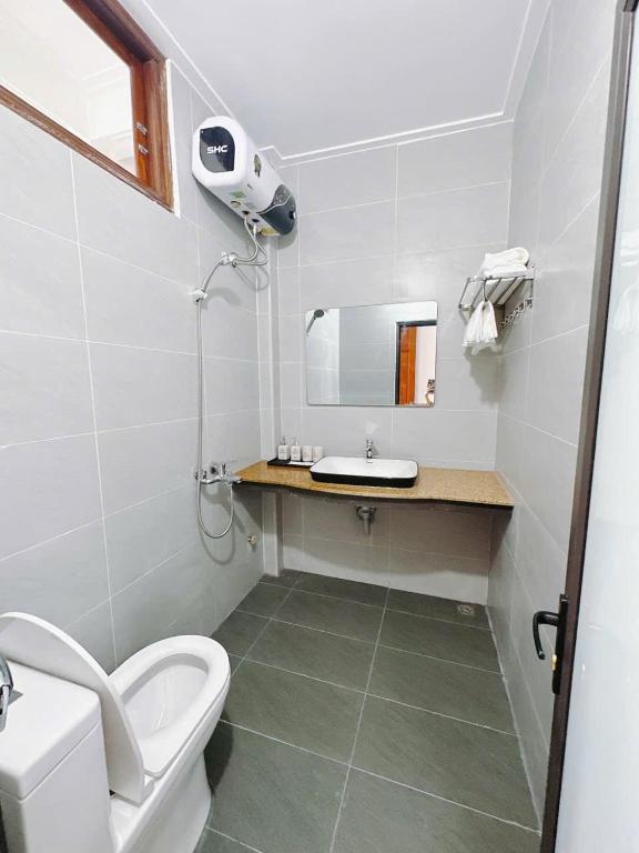 a bathroom with a toilet and a sink and a mirror at Bảo Yến HOTEL in Bản Khe Rạn