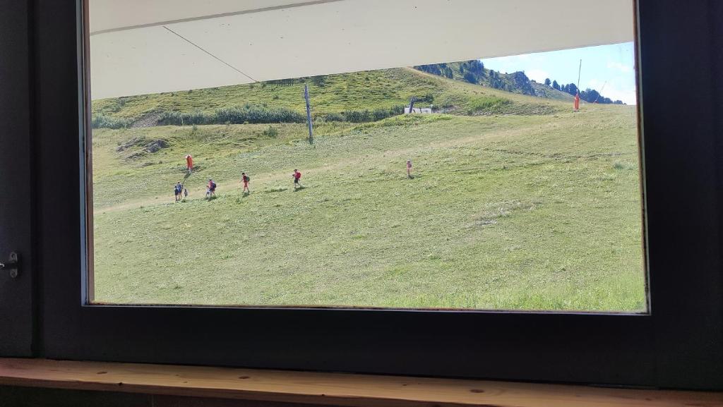 un groupe de personnes marchant dans un champ à travers une fenêtre dans l'établissement Studio Cosy 2100m pied des pistes-Direct to SKI slopes-SKI in SKI out-LA PLAGNE AIME 2000, à Aime La Plagne