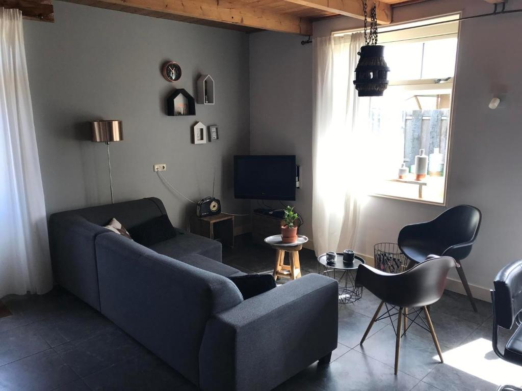 a living room with a blue couch and a tv at Apartment with Garden in Dutch Countryside in Callantsoog