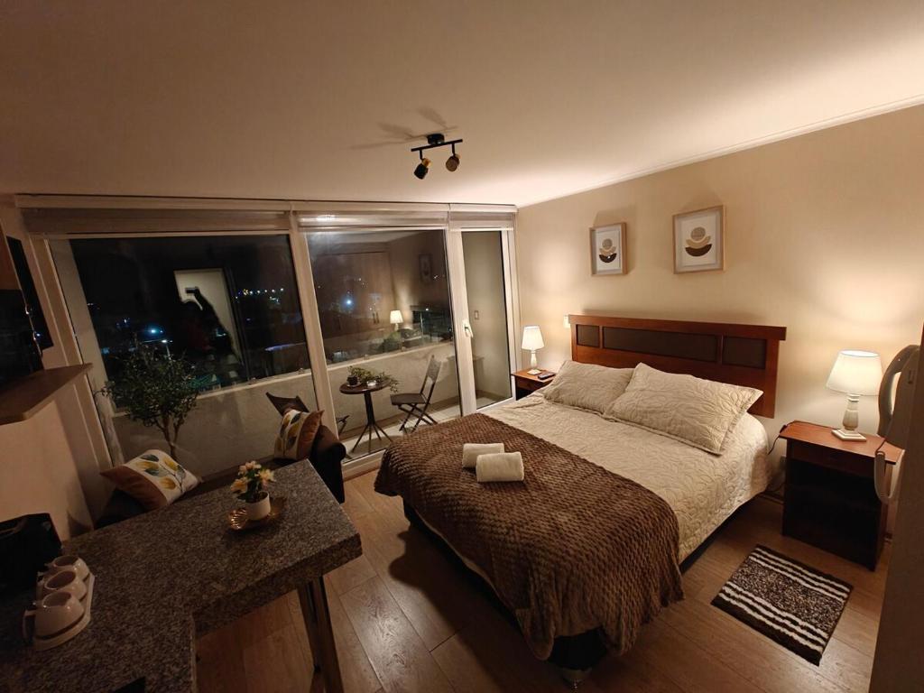 a bedroom with a large bed and a large window at Depto centro de chillan con estacionamiento in Chillán