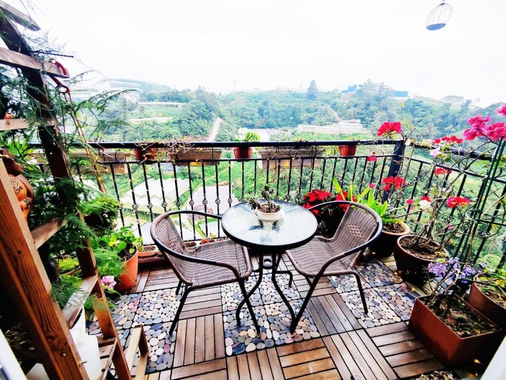 einen Tisch und Stühle auf einem Balkon mit Blumen in der Unterkunft #MyHighlandGetaway at OmniCassia Cameron Highlands in Cameron Highlands