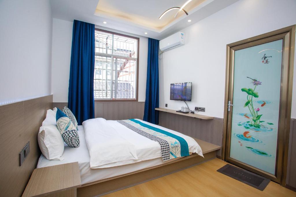 a bedroom with a bed with blue curtains and a window at 拾光有你民宿-Tianmen mountain-Book ticket service in Zhangjiajie