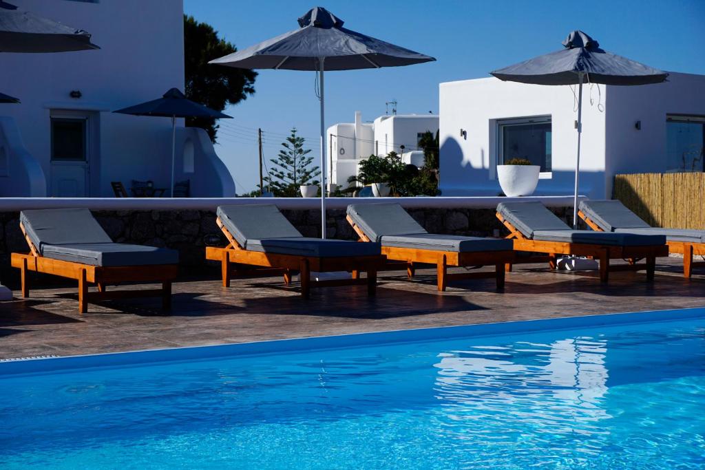 una piscina con sedie e ombrelloni accanto a una piscina di Casa Nostra Mykonos Boutique Rooms & Studios a Glastros
