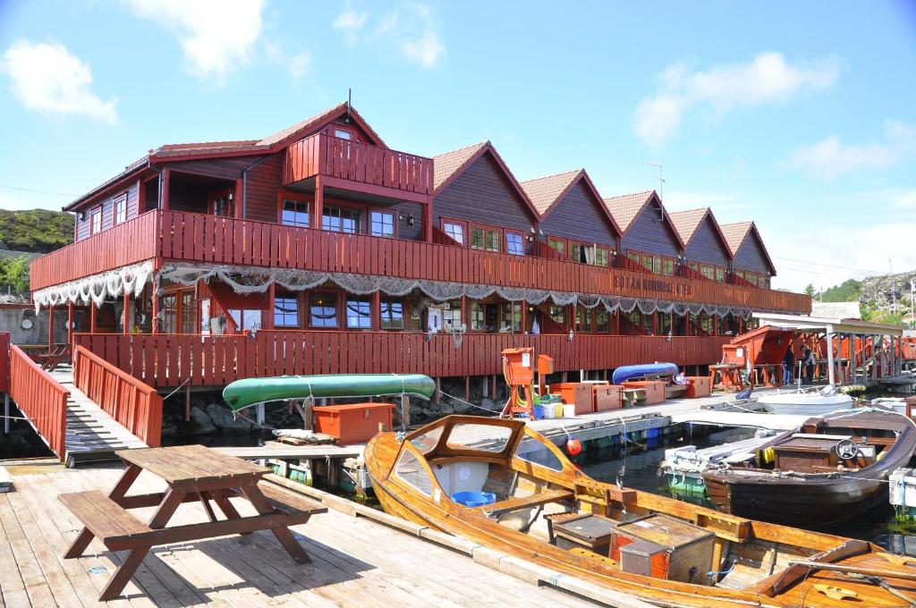 een groot gebouw met boten aangemeerd in een jachthaven bij Sotra Rorbusenter in Kåravika