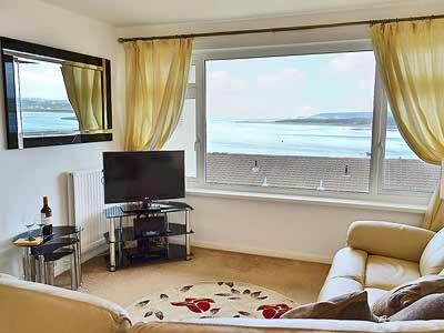 a living room with a couch and a large window at Sheerwater in Appledore