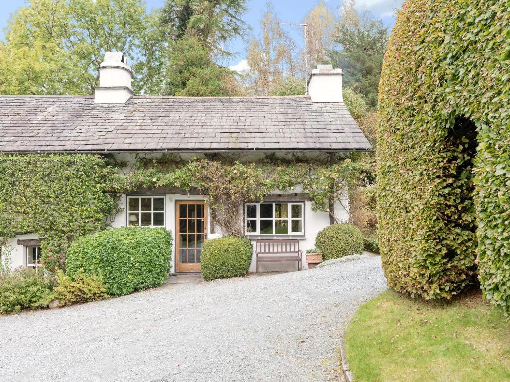 a cottage with a bench in front of a driveway at Rowlandson Ground Cottage in High Yewdale