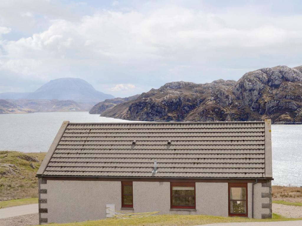 a small house in front of a body of water at Lochinchard Cottages in Kinlochbervie