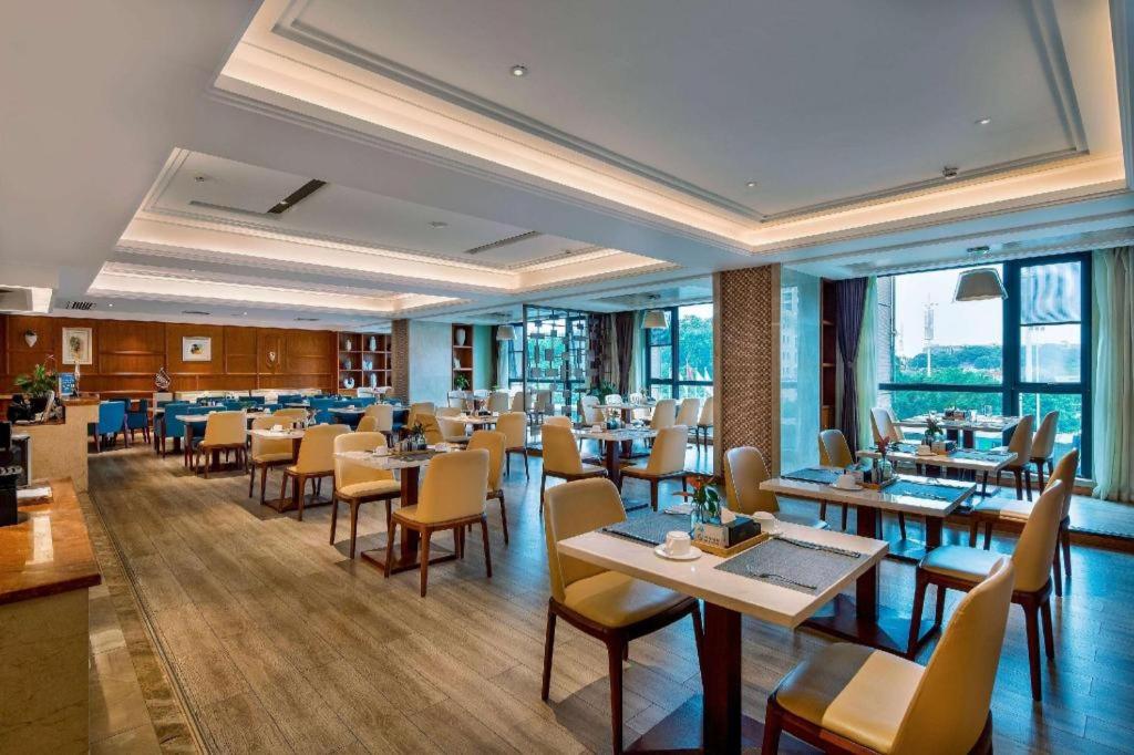 a dining room with tables and chairs and windows at Days Hotel by Wyndham Hunan Changsha Convoy in Changsha
