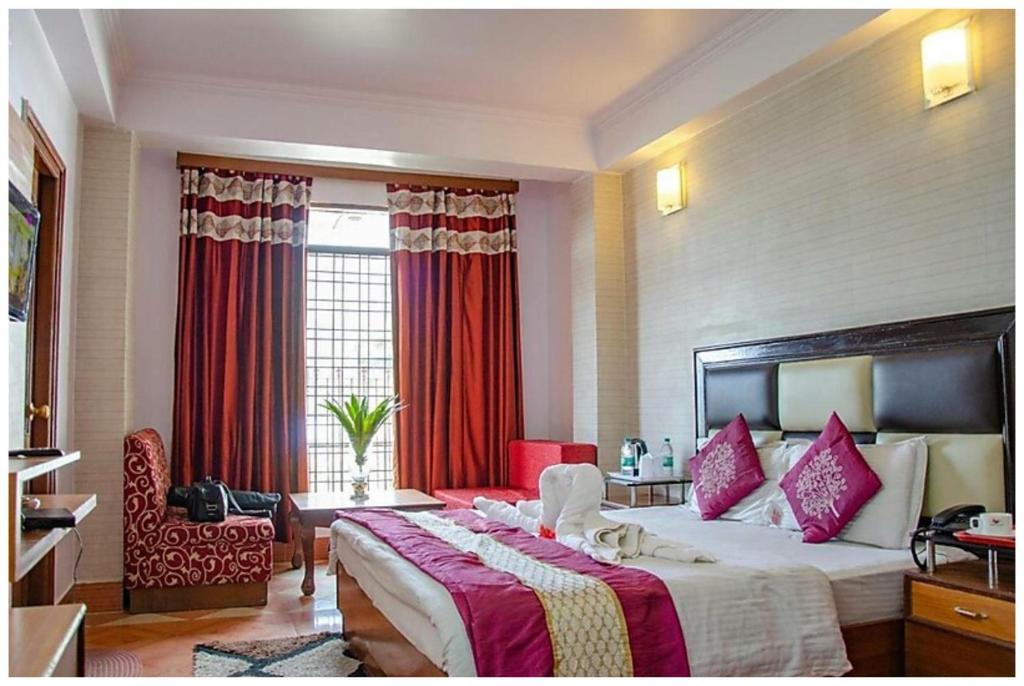 a bedroom with a large bed with red curtains at HOTEL THE ABHINANDAN PALACE Near Mall Road - Free Wi-Fi & Restaurant Facilities - Hygiene and Spacious Room - A Top Rated Hotel In Mussoorie in Mussoorie