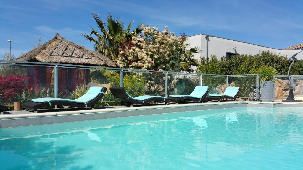 - un groupe de chaises assises à côté de la piscine dans l'établissement Entre Mer et Vignes, à Nissan-lez-Enserune