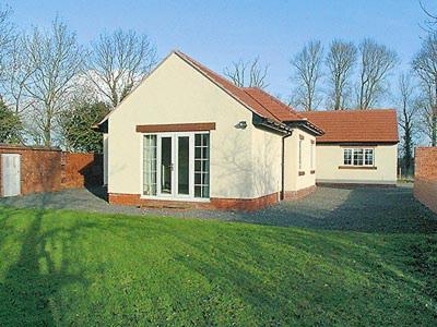 a small white house with a grass yard at Alby Bungalow in Wetheral