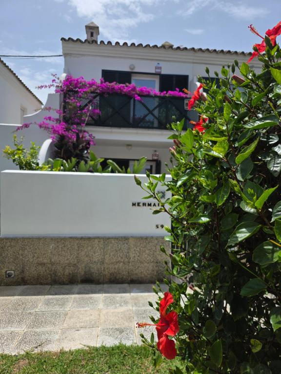 ein weißes Haus mit Blumen davor in der Unterkunft Mermaid Chalet Boutique La Barrosa mar a 200mt in Chiclana de la Frontera