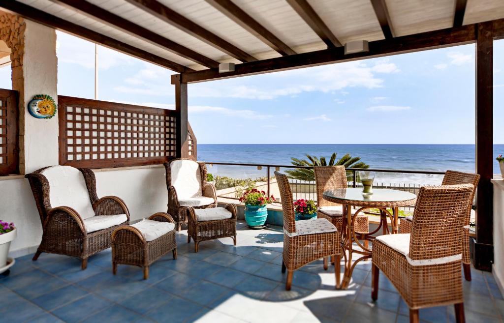 un patio con sillas, una mesa y el océano en Terrazza a mare Corallo, en Marina di Ragusa