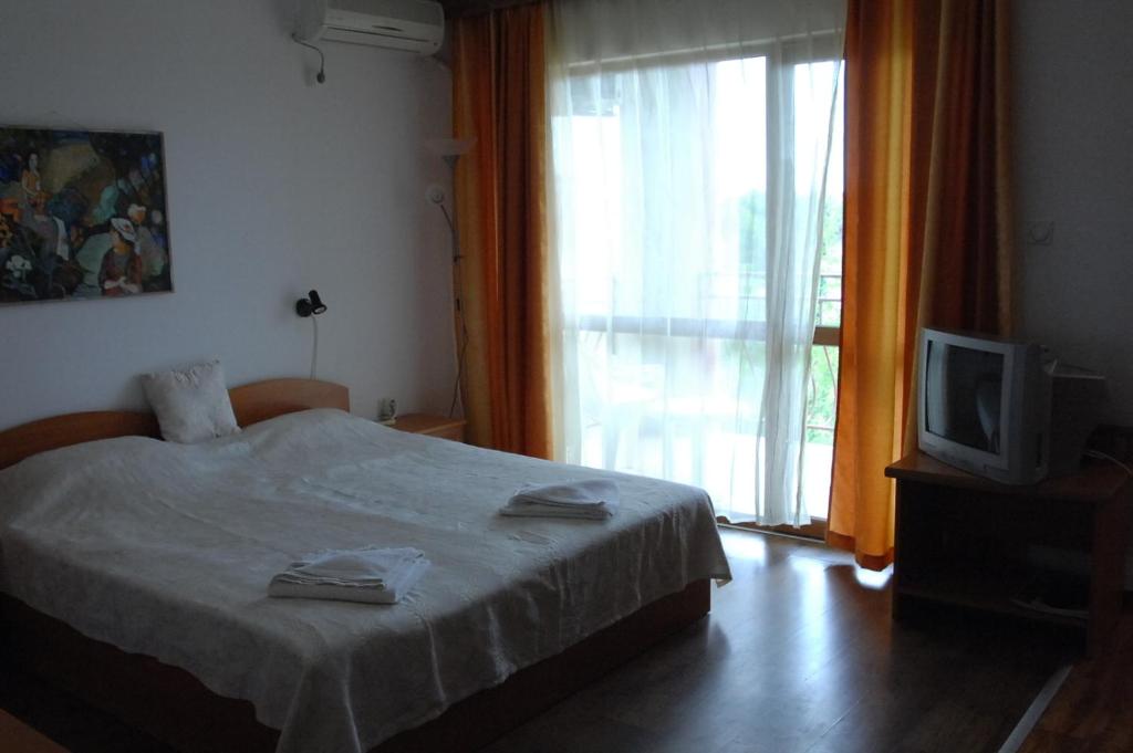 a bedroom with a bed and a tv and a window at Condo Hotel Valentina in Obzor