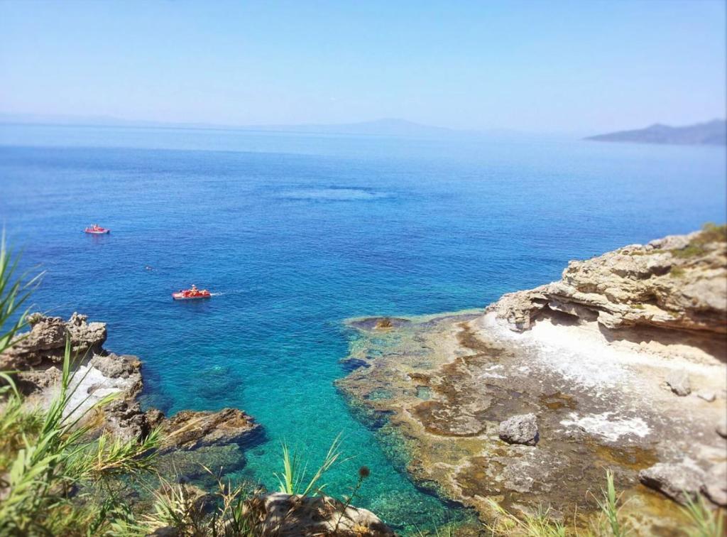 two boats in a body of water next to a cliff at Blue Lagoon Suites at Stoupa in Stoupa