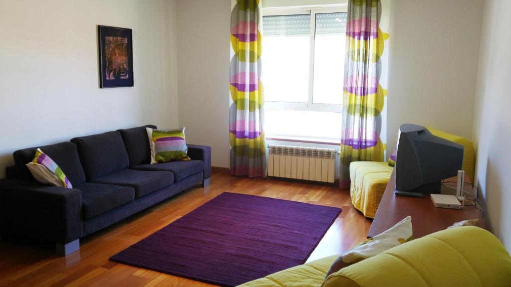 een woonkamer met een bank en een tv bij Tagus Life Apartment in Lissabon