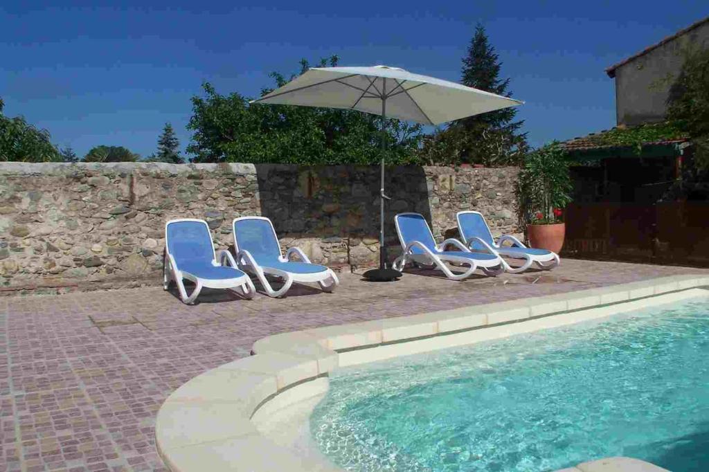 un grupo de sillas y una sombrilla junto a la piscina en Maison 225, en Prades