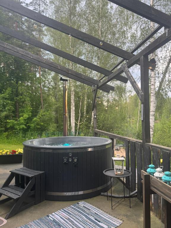 a hot tub on a deck with a pergola at Upesciema Cottage in Upesciems