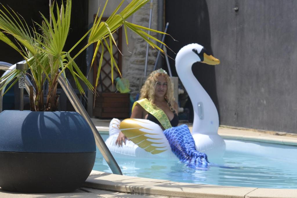 a woman sitting in a swimming pool next to a swan at Chambre d'hôte avec piscine partagé à disposition in Chef-Boutonne