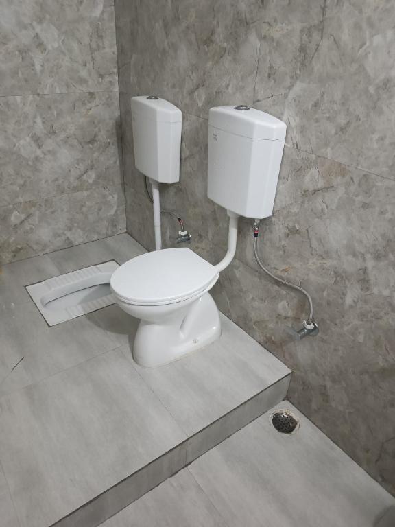 a white toilet in a bathroom with a stone wall at Home stay in varanasi by gaurav in Ahraurā Road