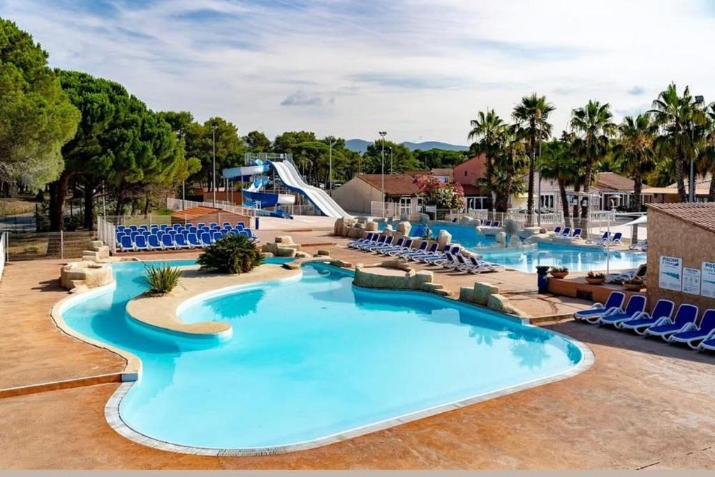 a pool at a resort with chairs and a slide at Le Chalet du Bonheur in Puget-sur Argens