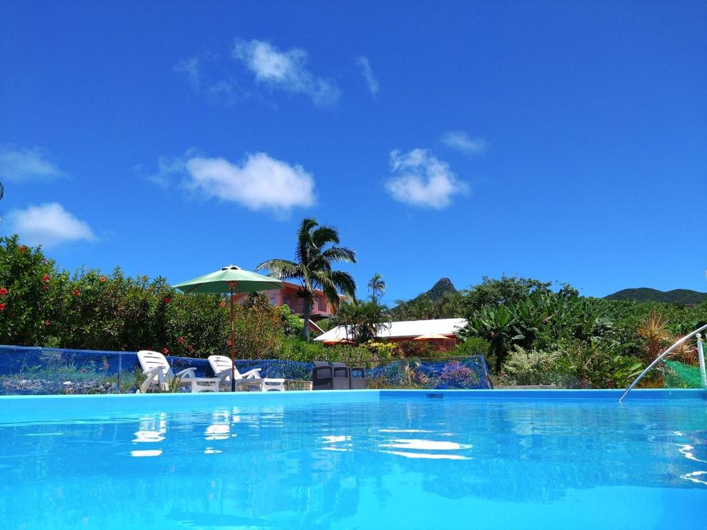 a swimming pool with two chairs and an umbrella at Beach Village Nosoko in Ishigaki Island
