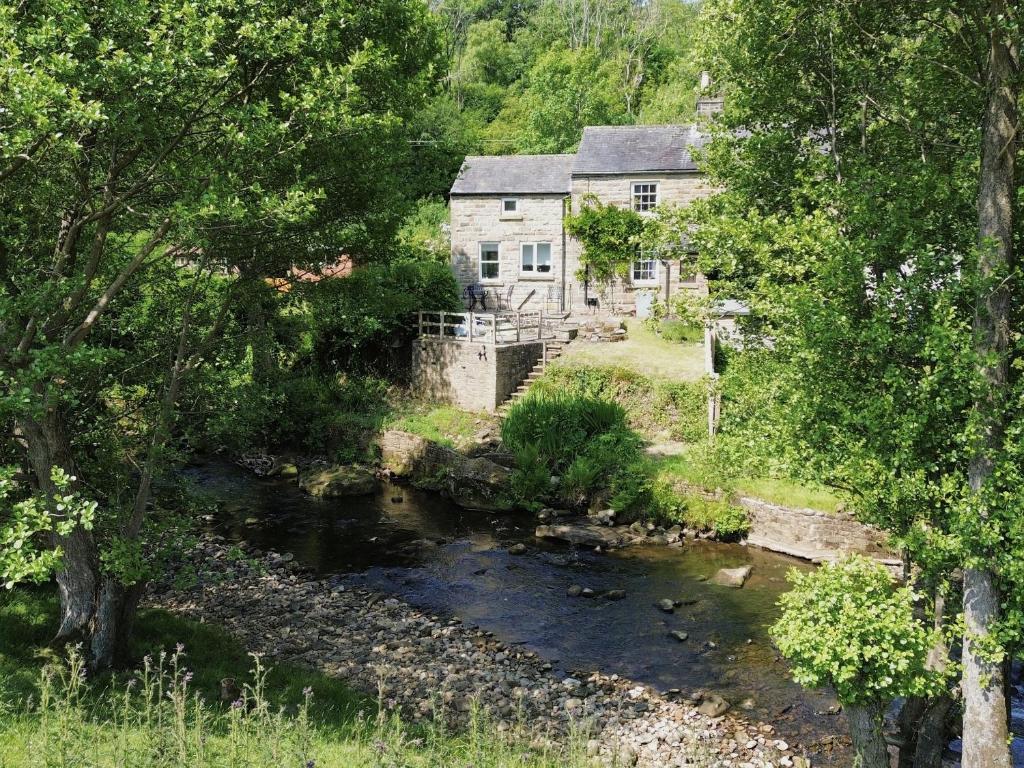 una casa e un ruscello di fronte a una casa di 2 Whinstone Cottage a Whitby