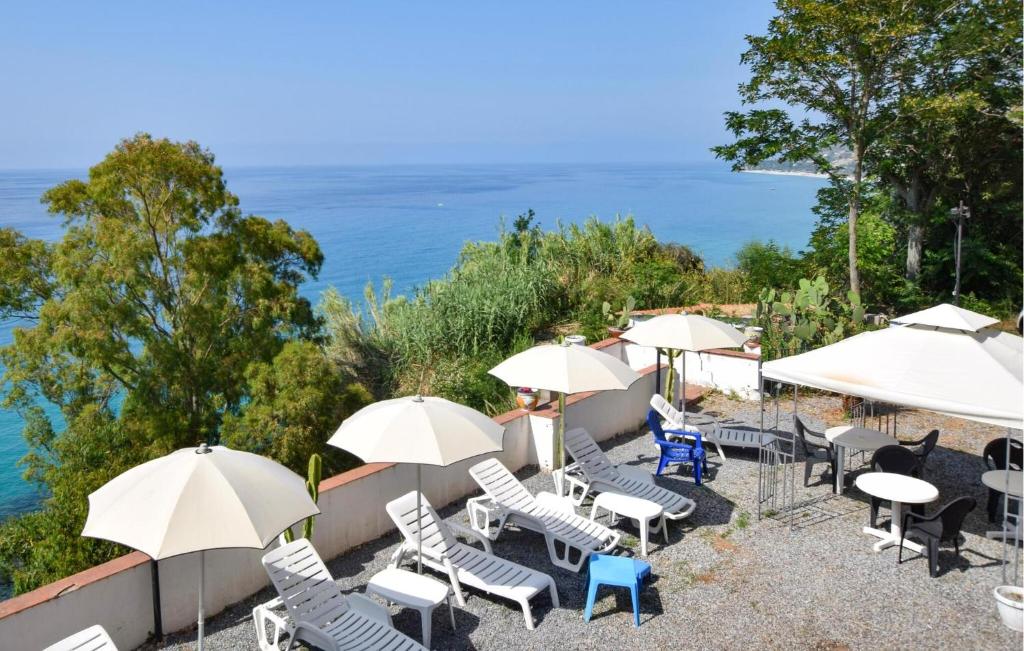 eine Terrasse mit Stühlen, Tischen und Sonnenschirmen in der Unterkunft Pet Friendly Apartment In Parghelia in Parghelia