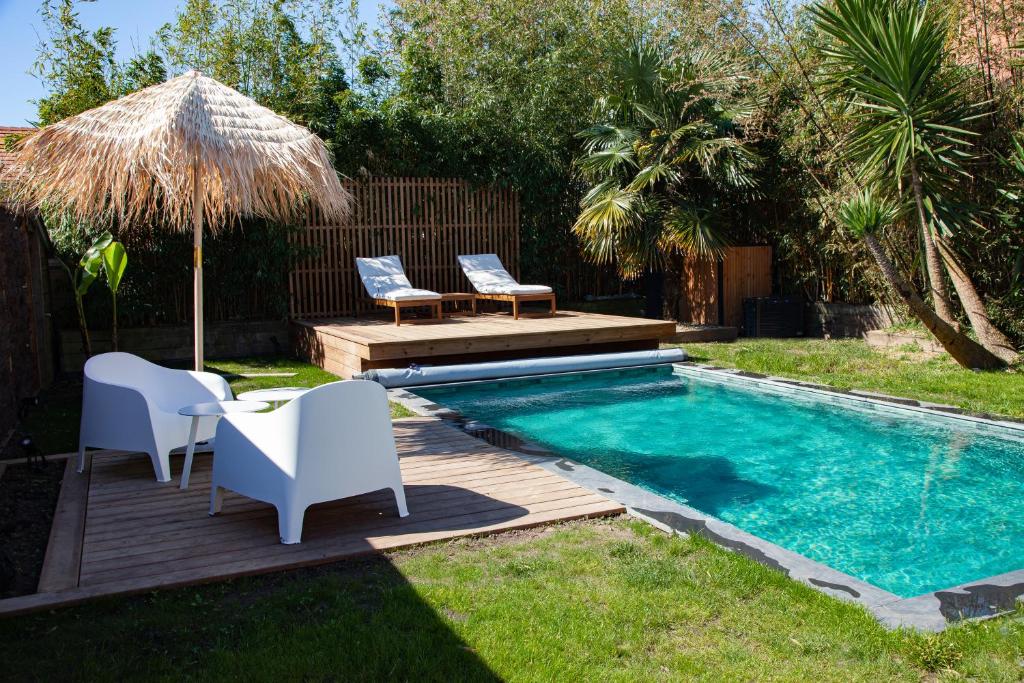 a swimming pool with chairs and a table and an umbrella at Villa avec piscine, Sainte Marguerite in Pornichet