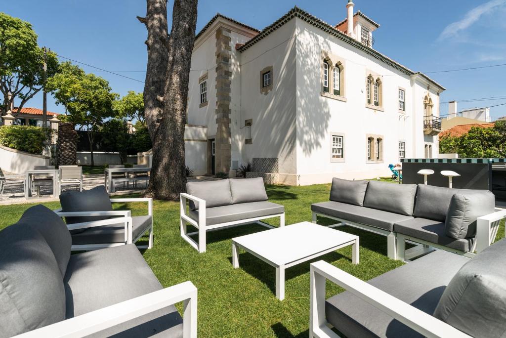 a yard with couches and tables and a white house at Villa Vasco da Gama in Cascais