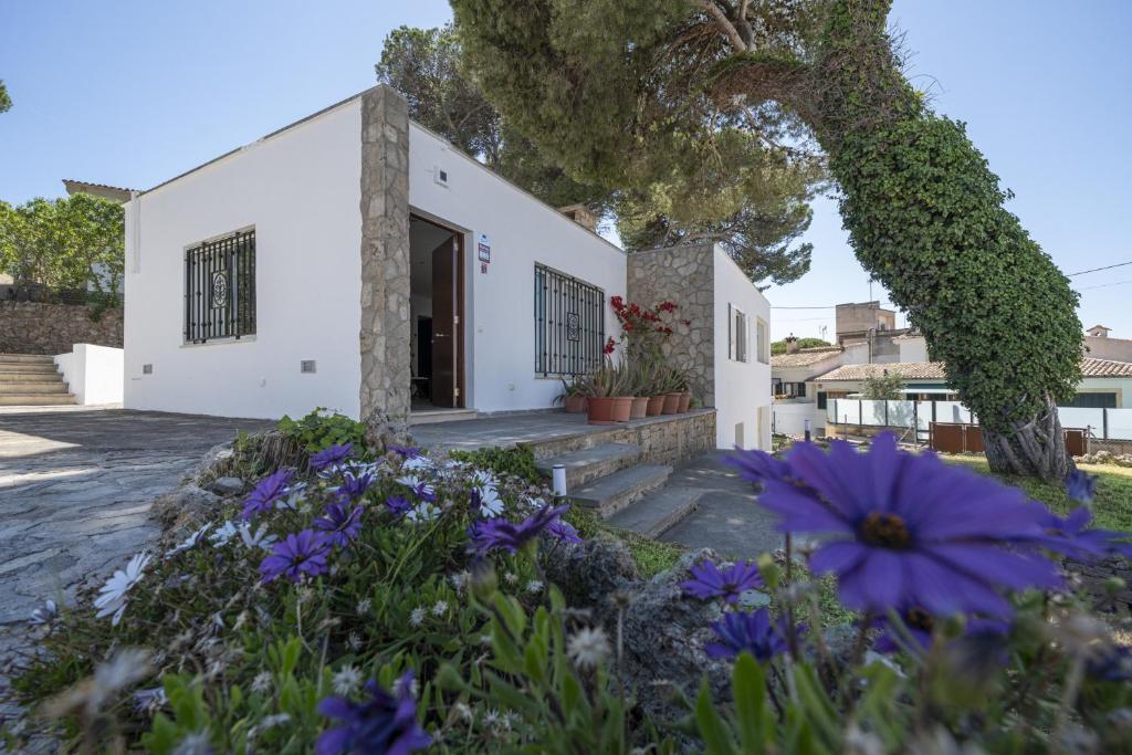 ein weißes Haus mit lila Blumen davor in der Unterkunft Casa Can Picafort in Can Picafort