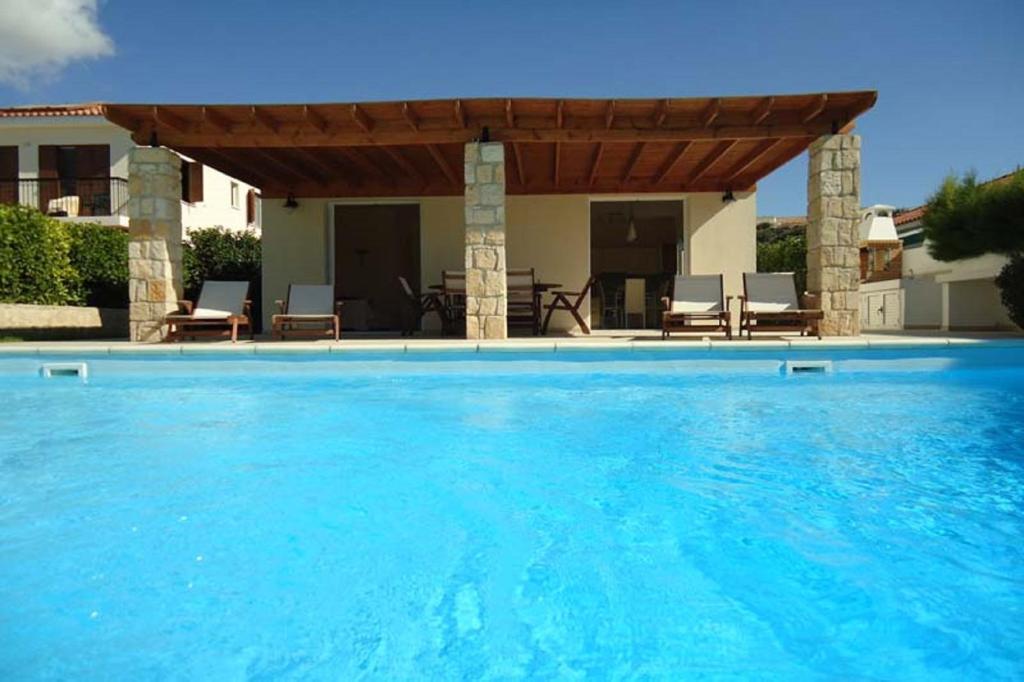 a large swimming pool with a wooden pergola at Katikies 20 in Pissouri